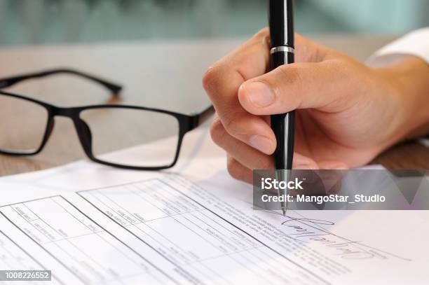 Closeup Of Woman Signing Document Stock Photo - Download Image Now - Document, Eyeglasses, Paper