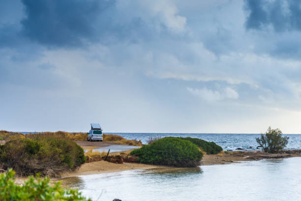 Camping trailer motorhome on seaside. Car on beach next to sea during cloudy summer weather