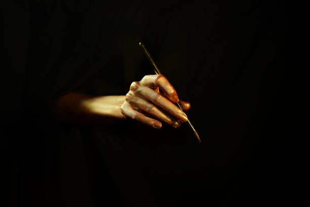 istock golden hand with brush on black background isolated 1008231492