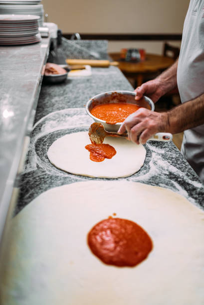 istock Chef adding tomato sauce. Italian pizza preparation. 1008231794