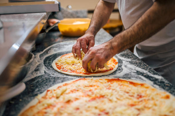 istock Chef in the kitchen putting the cheese on the pizza. 1008234758
