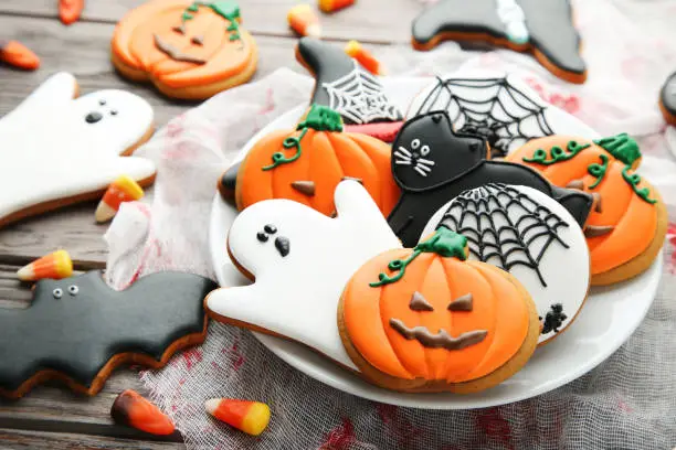 Photo of Halloween gingerbread cookies in plate on wooden table
