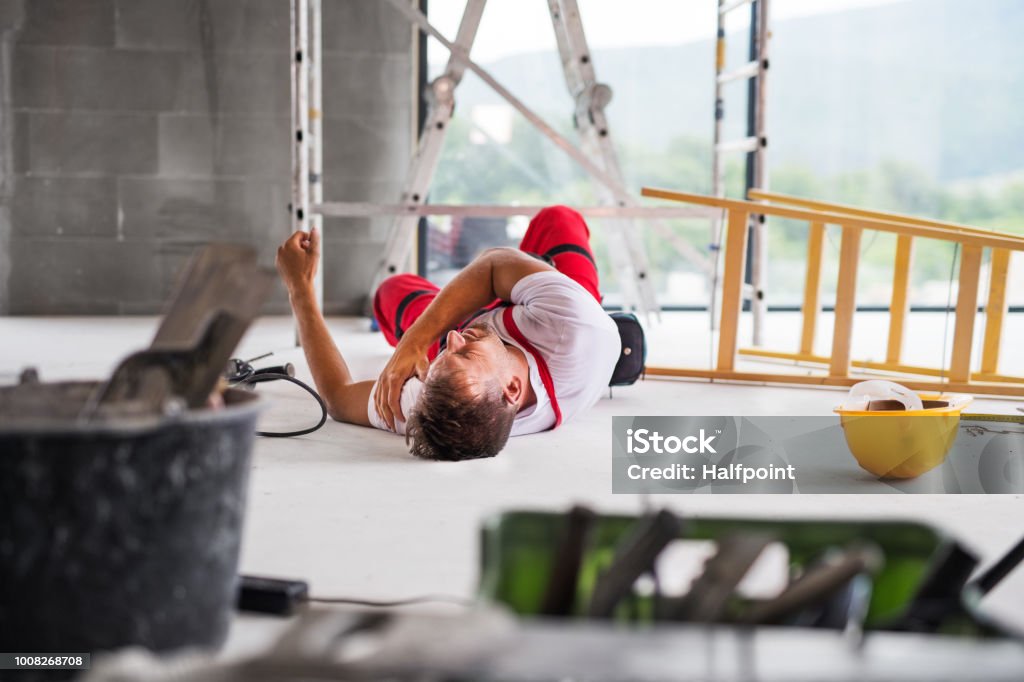 An accident of a man worker at the construction site. Accident of a male worker at the construction site. An injured man on the floor. Falling Stock Photo