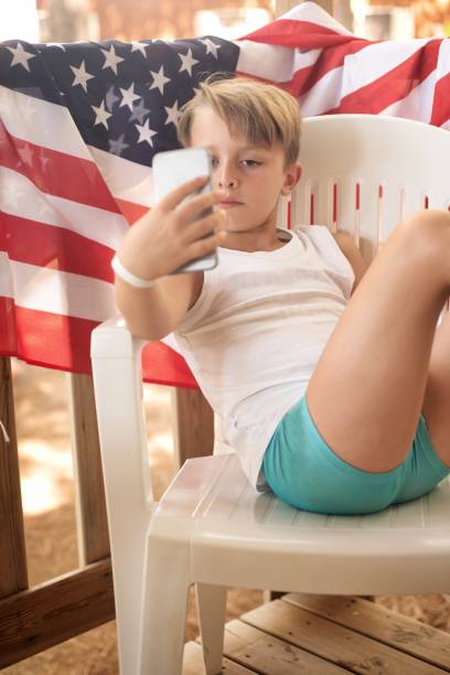 istock Child with a mobile phone. American Flag in the background. 1008271672