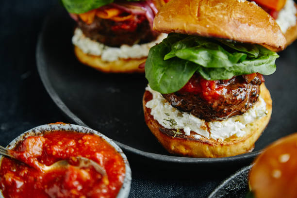 istock Burgers with grilled beef patties, cream cheese and spinach on classical bun. Dark rustic wooden background 1008275200