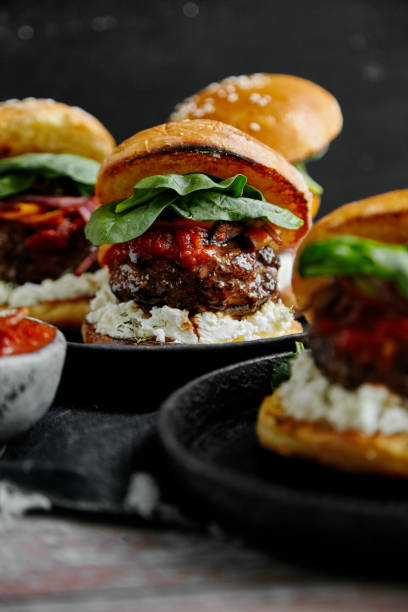 istock Burgers with grilled beef patties, cream cheese and spinach on classical bun. Dark rustic wooden background 1008275214