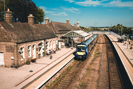 Train stopped at Inverurie Railway Station in Aberdeenshire, Scotland. The line connects the two main cities of Inverness, in the west, and Aberdeen in the east. On the left of the image is a small cafe known as Cocoworks. Inverurie town, set within rolling farmland and at a convenient commuting distance from the city of Aberdeen, has undergone a large expansion in house building in recent years, though still retaining its more traditional centre.