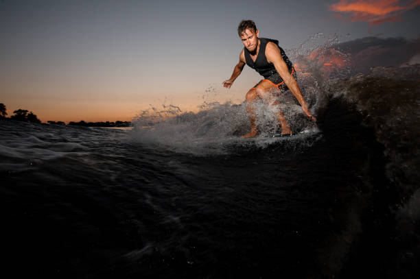 istock Active wake surfer jumping on board riding down the river waves at the sunset 1008284960