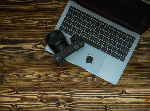 istock DSLR, mirror less Camera on Computer Electronic Devices laptop keyboard, on wood table, 1008287556