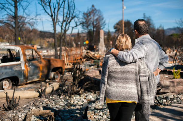 Couple checking ruins after fire disaster. Man and his wife owners, checking burned and ruined house and yard after fire, consequences of fire disaster accident. Ruins after fire disaster. fire natural phenomenon stock pictures, royalty-free photos & images