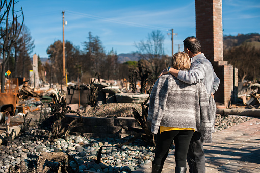 Man and his wife owners, checking burned and ruined house and yard after fire, consequences of fire disaster accident. Ruins after fire disaster.