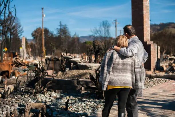 Photo of Man and his wife owners, checking burned and ruined house
