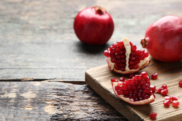 istock Ripe and juicy pomegranate with cutting board on grey wooden table 1008293512