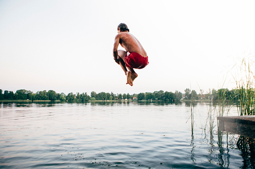 istock cannonball: young man jumps into a lake 1008294396