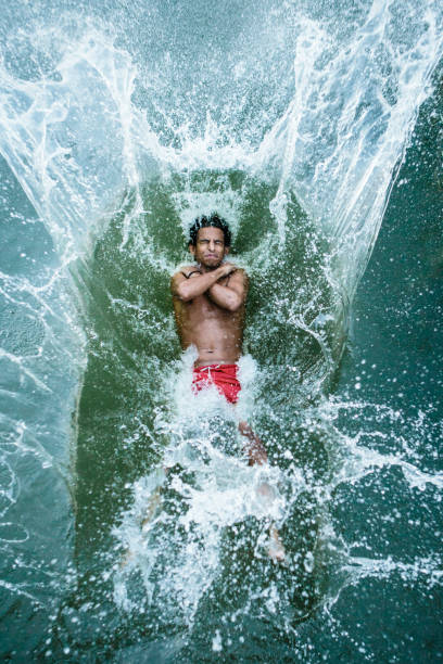 young man jumps backwards into a lake, water splashes around