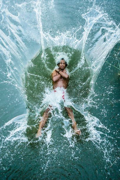 young man jumps backwards into a lake, water splashes around young man jumps backwards into a lake, water splashes around person falling backwards stock pictures, royalty-free photos & images