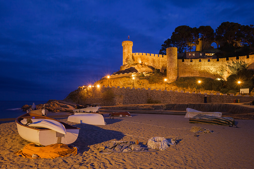 Spain, Costa Brava, Tossa de Mar by night, castle (walled Old Town - Vila Vella), boats on a beach