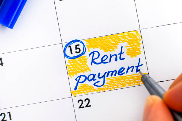 Woman fingers with pen writing reminder Rent Payment in calendar. stock photo