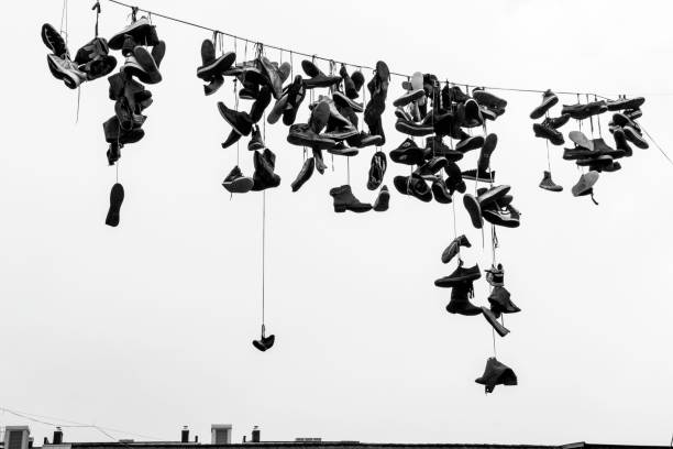 Multiple Shoes Hanging From an Electrical Cable in a City.