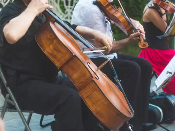 Photo of cellist musician group perform music in the street, close up man playing violin