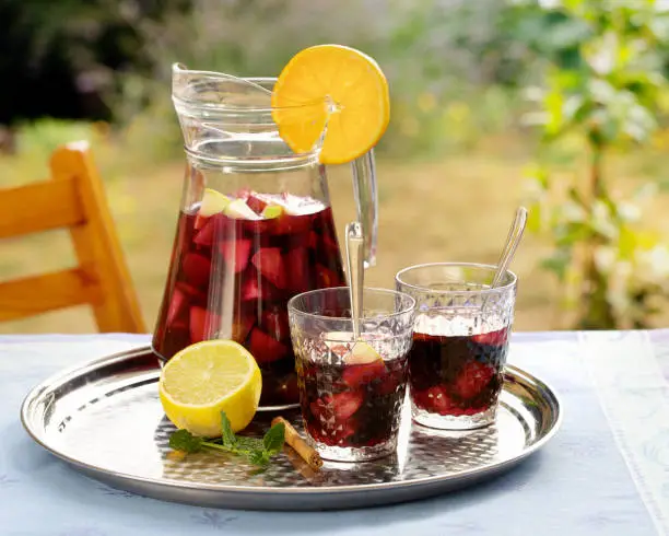 Refreshing homemade sangria with summer fruits in pitcher and glasses