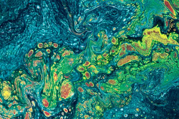 Marbling textured creative background. Mixing green, blue,   yellow and red paints. Lines and bubbles.  Liquid paint.