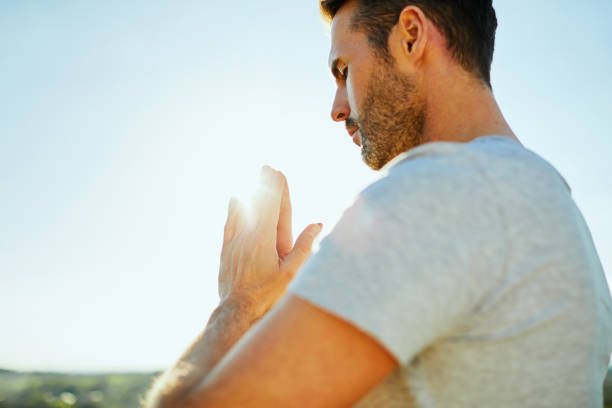 Portrait of man praying outdoors on sunny day