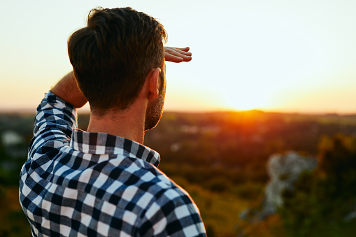 Hombre de pie en el Prado en las montañas y admirar la puesta del sol photo