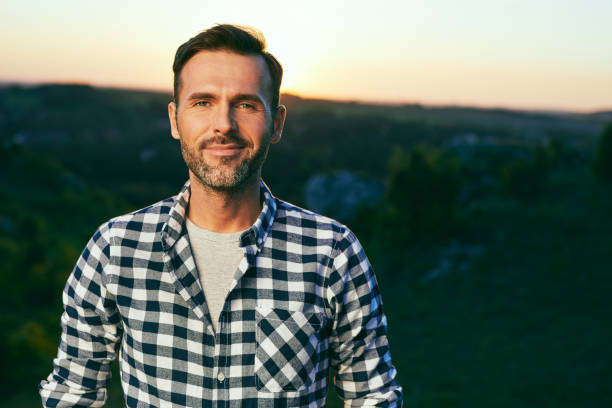 Portrait of handsome man standing on meadow surrounded by nature