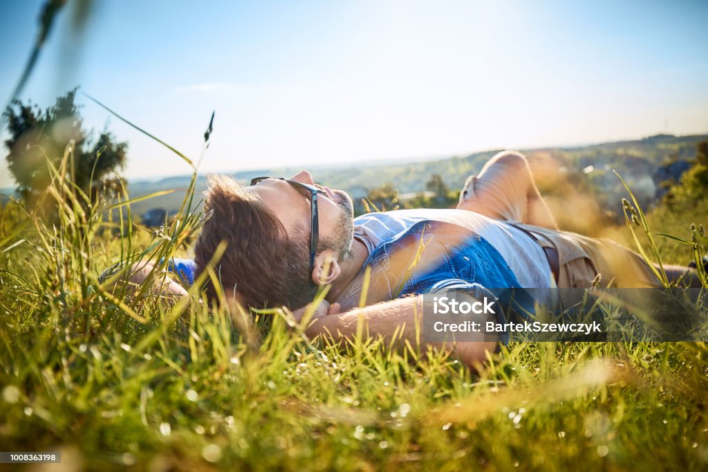 Homme étendu dans l’herbe sur voyage dans les montagnes de randonnée - Photo de Hommes libre de droits