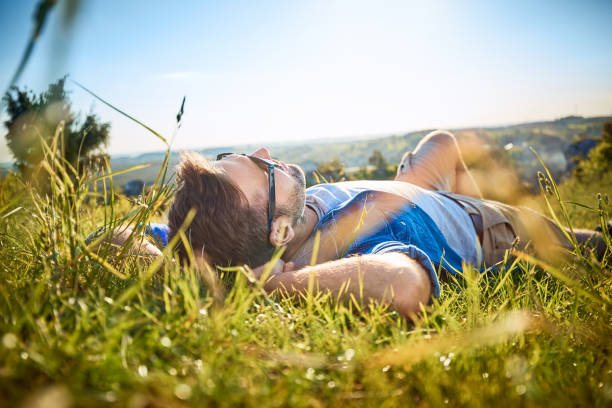 Man lying in grass on hiking trip in the mountains Man lying in grass on hiking trip in the mountains lying down stock pictures, royalty-free photos & images