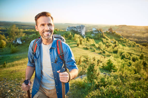 istock Smiling man hiking in the mountains using poles and looking away 1008363622