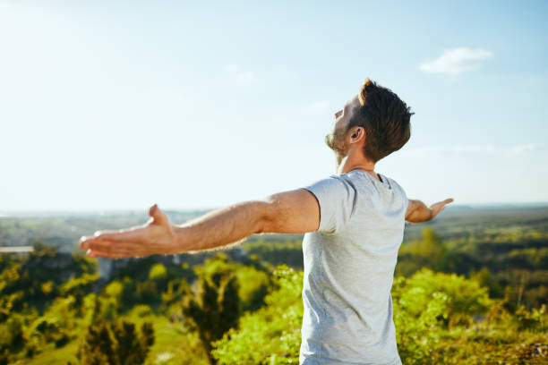 istock Man extending arms and admiring the view on sunny day in a forest 1008363880