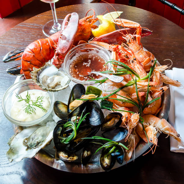 seafood platter fresh seafood platter with red lobster, langoustine, prawns, mussels, oysters, clams, with a tartare and sweet chilli sauce on a wooden background lobster seafood photos stock pictures, royalty-free photos & images