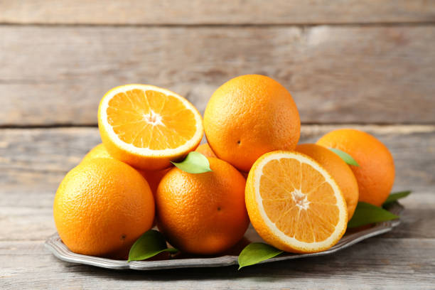 istock Orange fruit with green leafs in tray on grey wooden table 1008373076