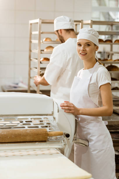 istock female baker with industrial dough roller at baking manufacture 1008375738