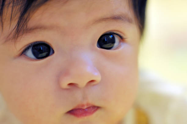 Baby with big blue eyes explores the world on a cozy blanket, radiating innocence and joy