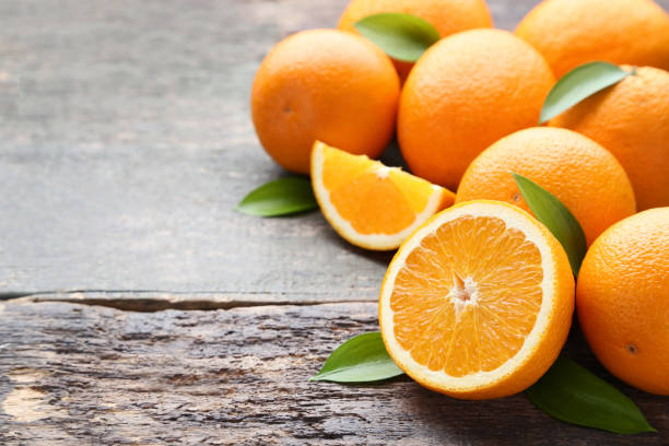 istock Orange fruit with green leafs on grey wooden table 1008376602