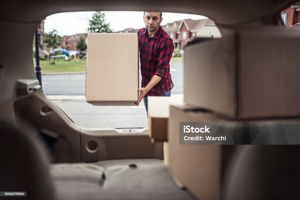 Man loading boxes in to his car. Caucasian man loading moving boxes in to his car. View from the car trunk Car Trunk Stock Photo