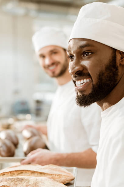 istock handsome young bakers in hats at baking manufacture 1008379940