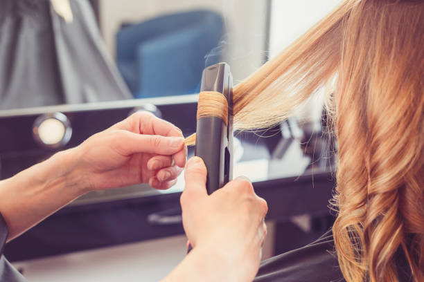fryzjer tworzący fryzurę dla klienta - straightener zdjęcia i obrazy z banku zdjęć