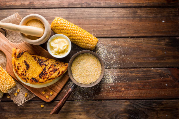 Typical Venezuelan cuisine, Top view of a wooden table with several ingredients for the preparation of Cachapas with cheese, corn, butter, ground corn and white cheese stock photo