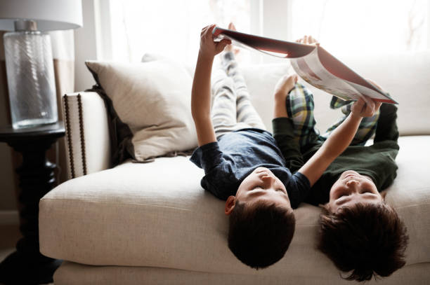 Two confident serious boys friends in white shirt talking isolated on black background, pointing on book, speaking. Children debating argument. Education discussion concept. Copy text space for ad