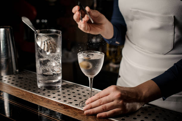 istock Bartender girl throwing into the cocktail one olive with tweezers 1008405742
