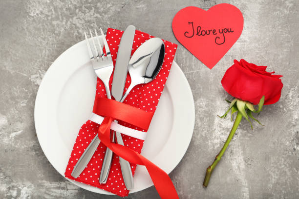 istock Kitchen cutlery in white plate with red rose on wooden table 1008406102