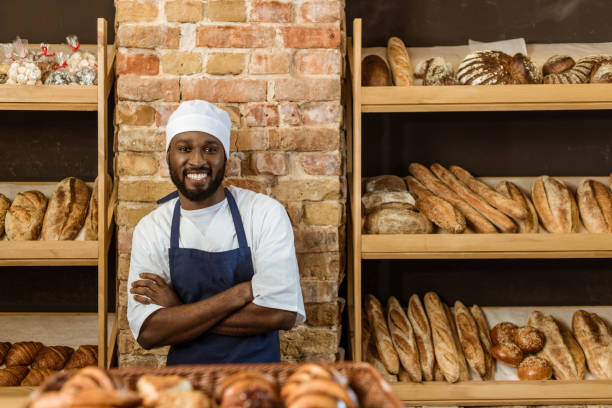 istock handsome smiling baker with folded arms standing at pastry store 1008408640