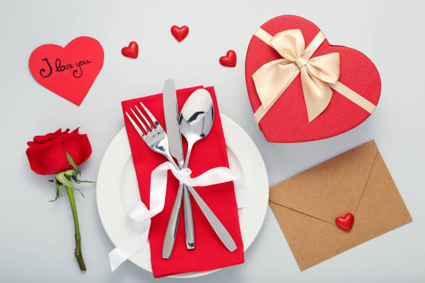 istock Kitchen cutlery in white plate with red rose and gift box on grey background 1008409060