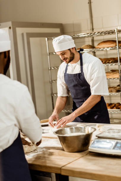istock handsome bakers kneading dough together at baking manufacture 1008409458