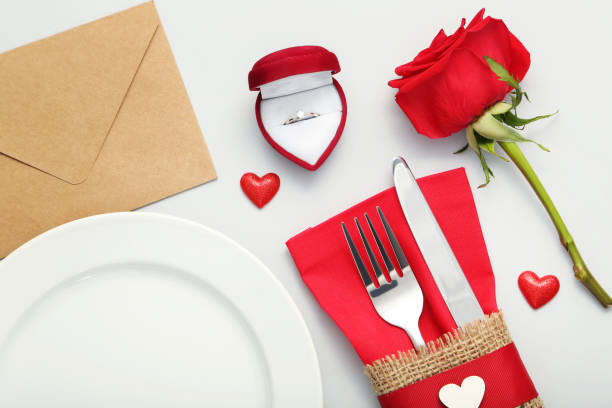 istock Kitchen cutlery with envelope, silver ring and red rose on grey background 1008409612