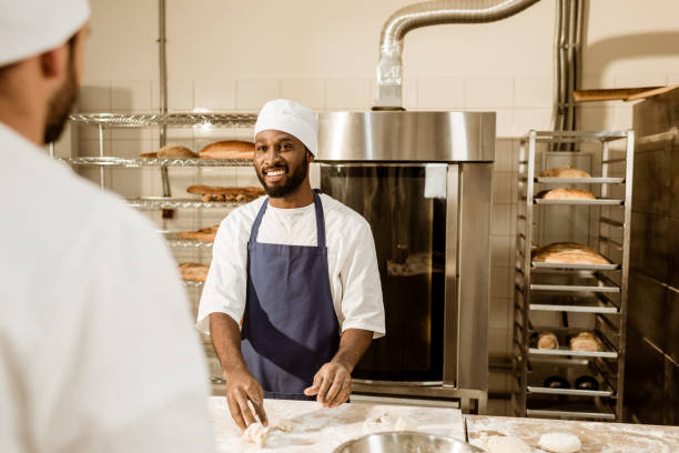 istock young bakers kneading dough together at baking manufacture 1008413328